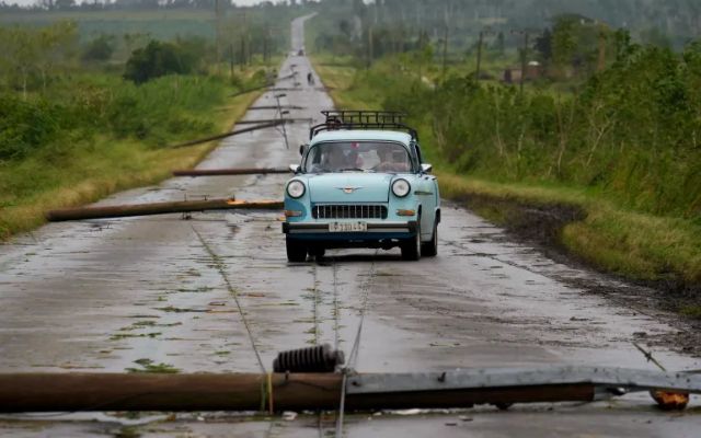 People drive along a road littered with fallen power lines