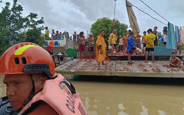 Residents stand on the roof of their submerged houses