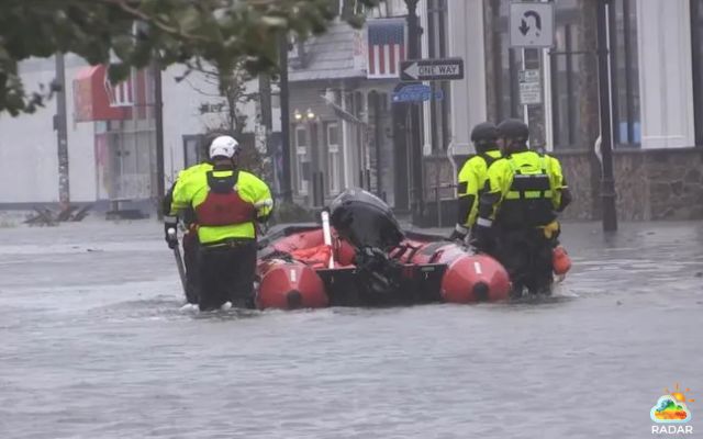 Responders wade through deep floodwaters with a rescue boat
