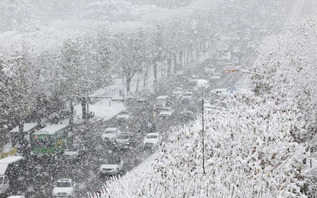 Cars move slowly on a snow-covered road